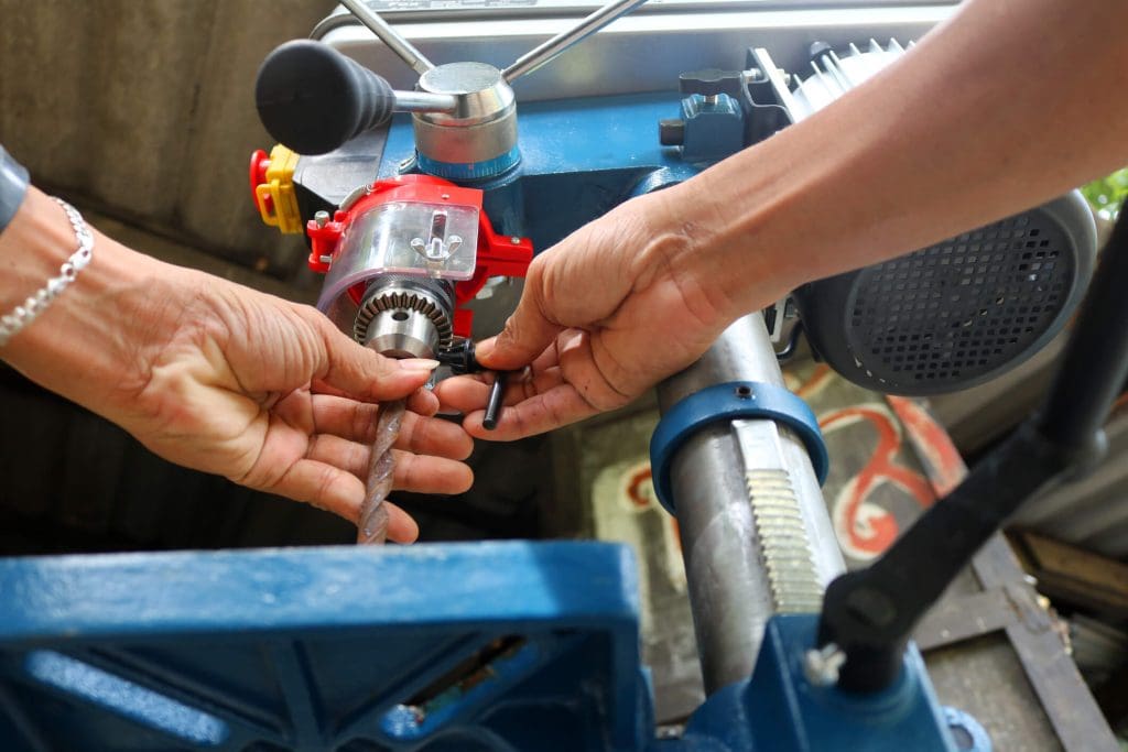 dreamstime_m_95443039 Drill presses machine with machinist. Worker use the Drill presses machine in the workshop.